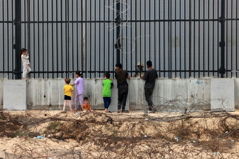 Displaced Palestinian children chat with an Egyptian soldier through the fence separating Egypt and Rafah in the southern Gaza Strip
