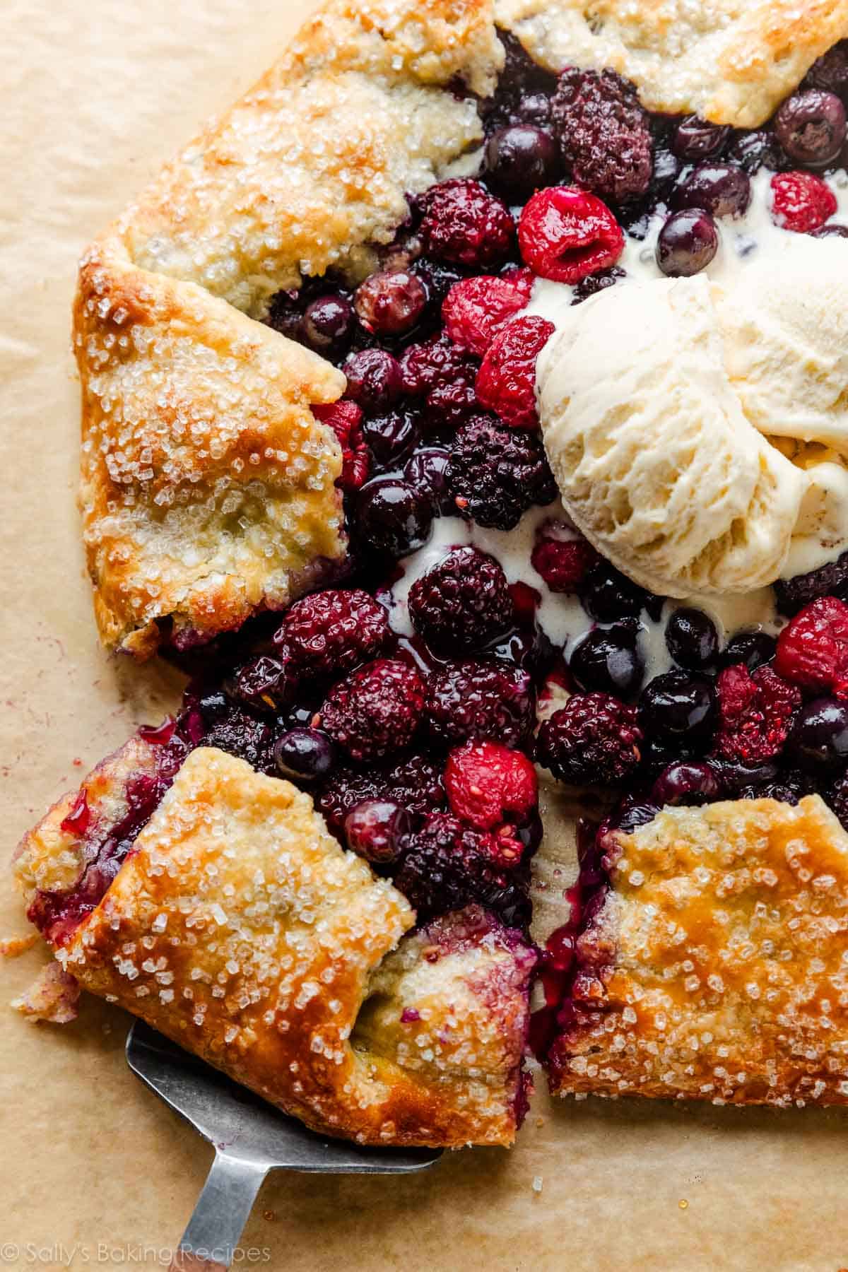 sliced mixed berry galette with melted vanilla ice cream on top.