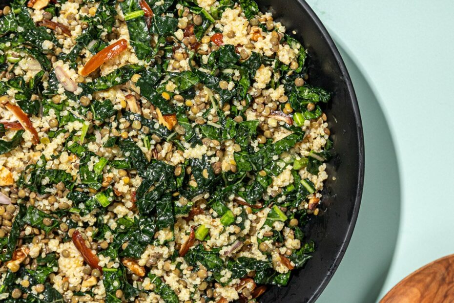 kale, lentil and quinoa salad in black bowl with wooden spoon