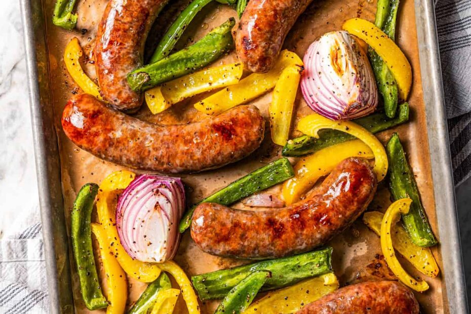 Baked Italian sausage with bell peppers and onions on a baking sheet.