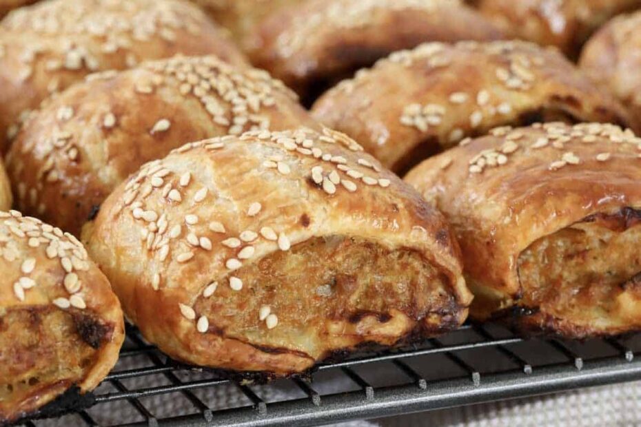 Crispy pork sausage rolls cooling on a wire rack.