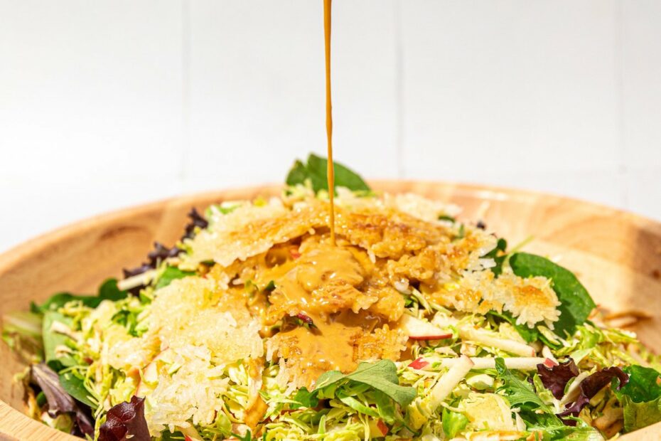 hand pouring dressing on crispy rice and brussels sprouts salad