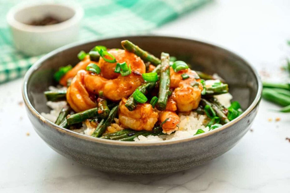 Homemade hunan Shrimp with green beans served over white rice topped with green onions.