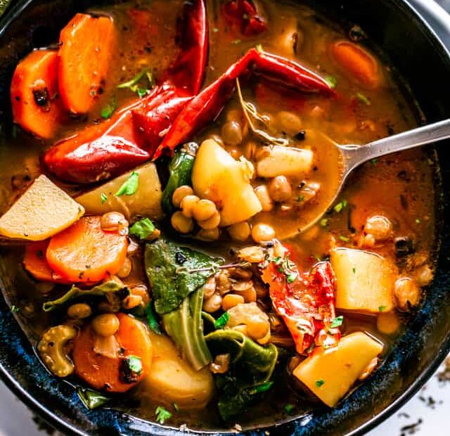 Overhead view of lentil soup in a black stoneware bowl.