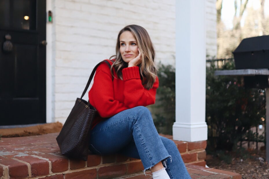 Woman wearing jeans, red sweater, and loafers