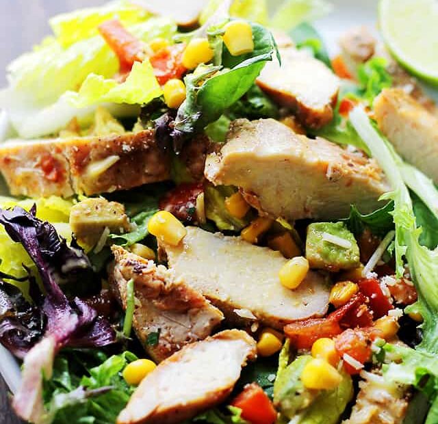 Close up of chipotle chicken salad with a side of dressing in a white bowl.