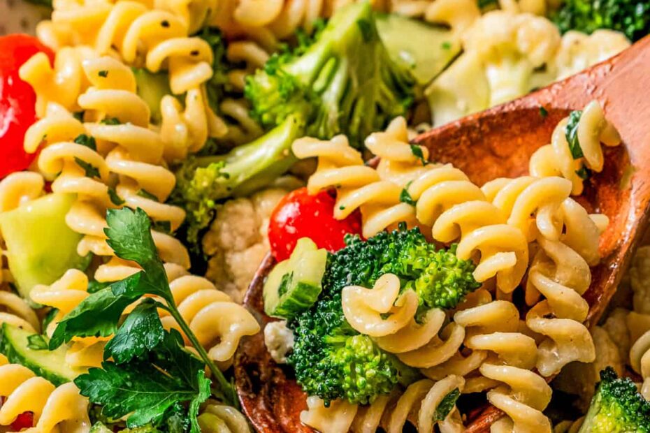 An easy pasta salad served in a stoneware salad bowl with a wooden serving spoon.