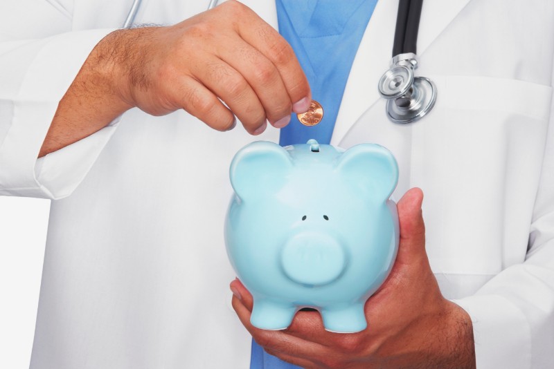 A doctor putting a penny in a blue piggy bank to help illustrate How Much Does Bariatric Surgery Cost Out Of Pocket