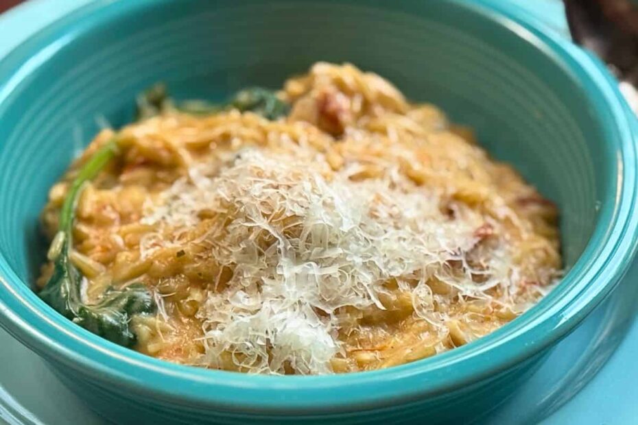 cheesey chicken and orzo in a blue dish with spinach and a spoon