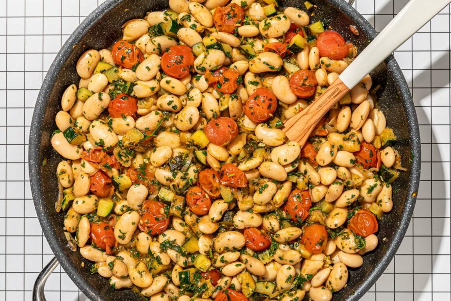 white bean and tomatoes in skillet with plate of sliced bread
