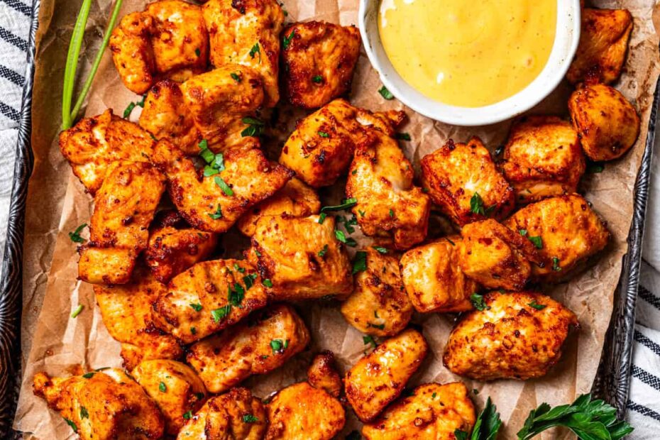 Air fried chicken bites are served on a tray next to a bowl of honey mustard sauce.