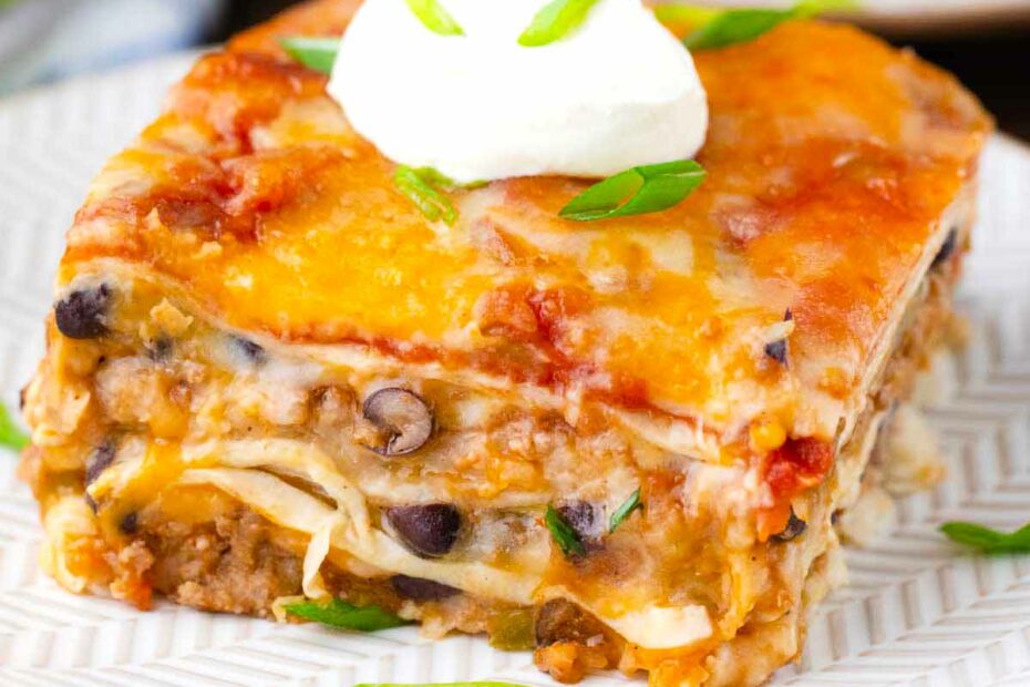 A slice of cheesy taco lasagna topped with crema fresco.