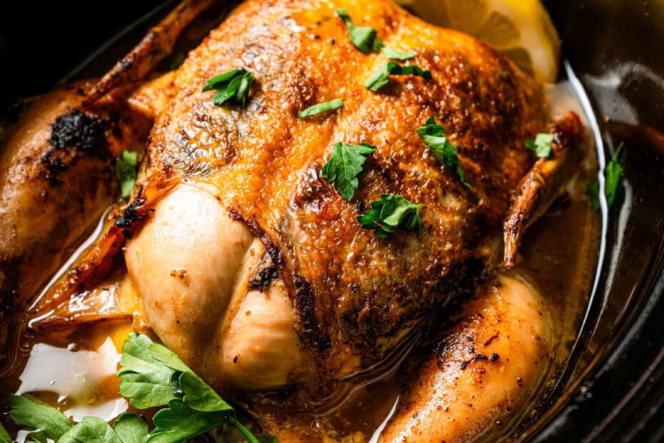 A cooked whole chicken inside the crock pot.