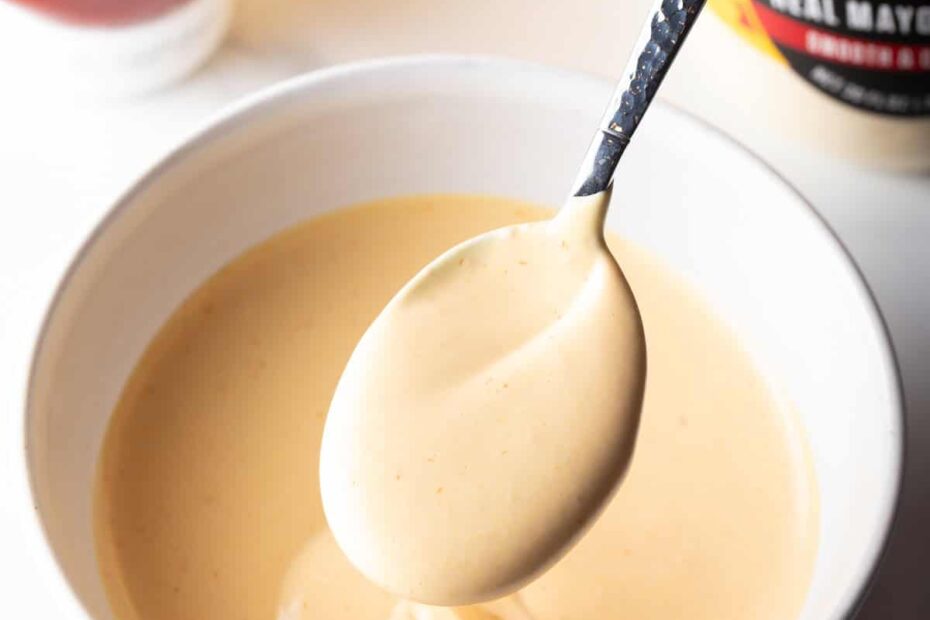 Spoon of burger sauce held over a bowl of sauce.