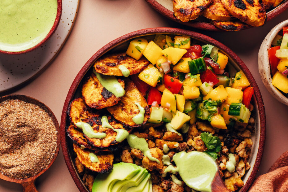 Drizzling green tahini sauce onto a Jerk Tofu & Roasted Plantain Bowl