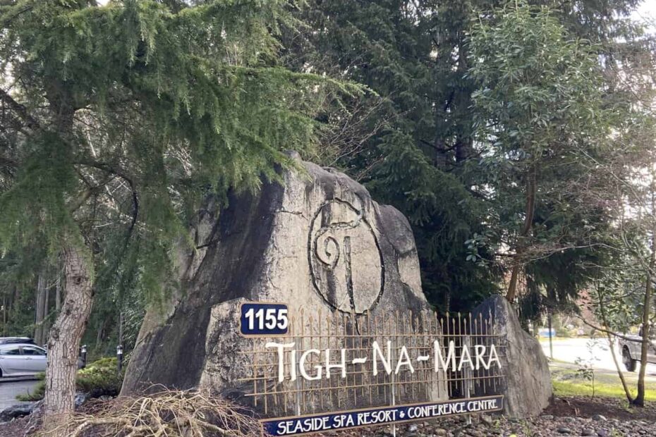 The sign for Tigh Na Mara Resort in Parksville, BC on Vancouver Island. The sign is on a rock in front of tall trees at the entrance to the resort.
