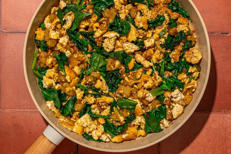 tofu, spinach and potatoes in a skillet on red brick