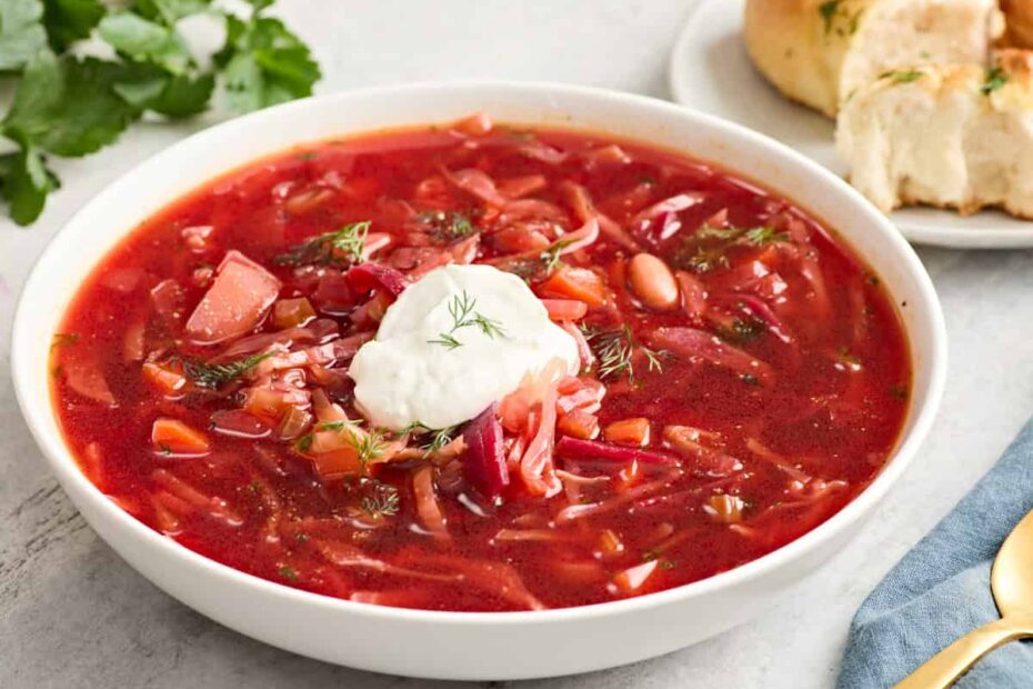 Side view of a bowl of borscht topped with sour cream.