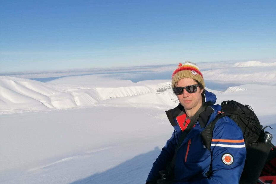 Eoin Murphy on a snowy mountain with a clear blue sky behind him.