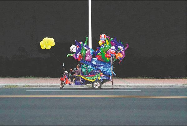 Scenes of night life in the suburbs of Guangzhou, Guangdong province, captured by Yan: A woman selling balloons on a motorcycle. [Photo by YAN JIACHENG/FOR CHINA DAILY]