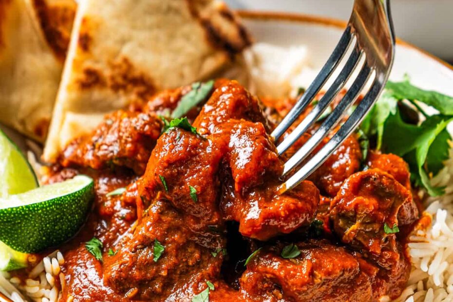 Beef madras curry served over a bowl of rice with a side of naan bread.