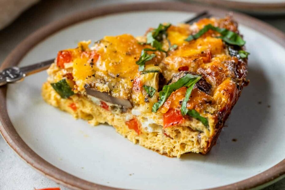 a slice of a crustless vegetable quiche on a white plate.