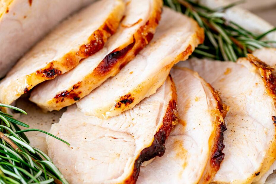 Slices of roasted turkey breast shown close up with visible herbs and a natural backdrop.
