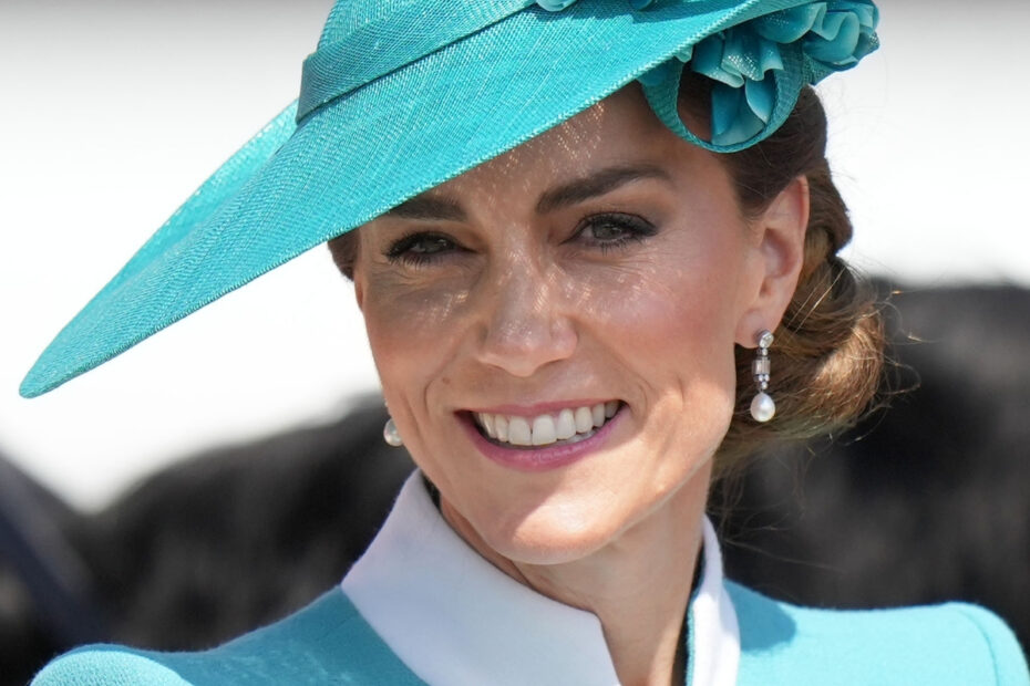 The Princess of Wales - Kate Middleton - smiling wearing formal attire and a hat in the colour teal