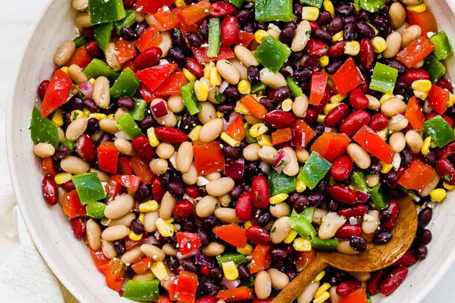 A wooden serving spoon in a serving bowl of Mexican Bean Salad.