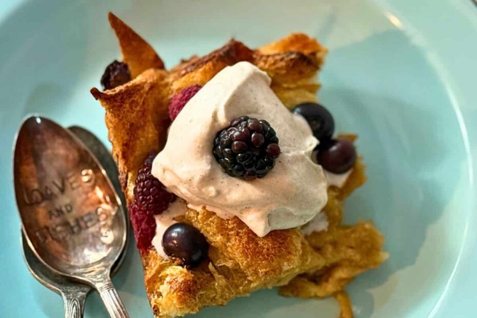 french toast on a blue plate with two spoons, whipped cream and berreis