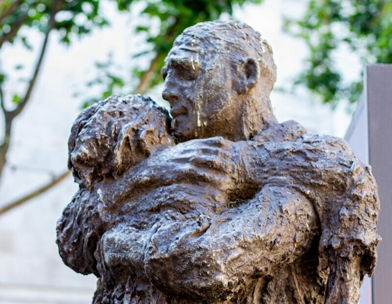 A bronze sculpture depicts a man hugging a child.
