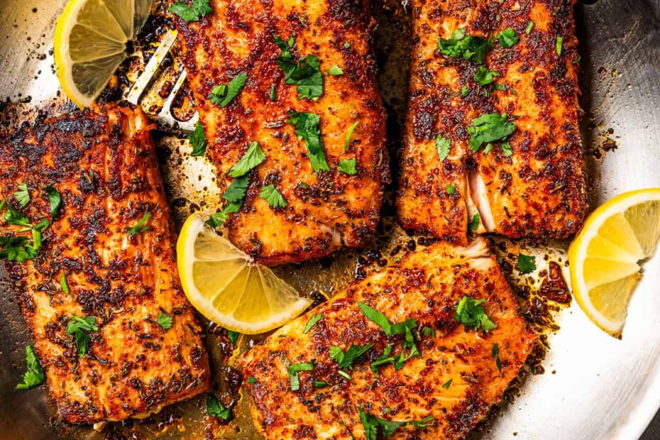 Mahi mahi in a skillet garnished with fresh herbs and lemon wedges. Photo by diethood.com