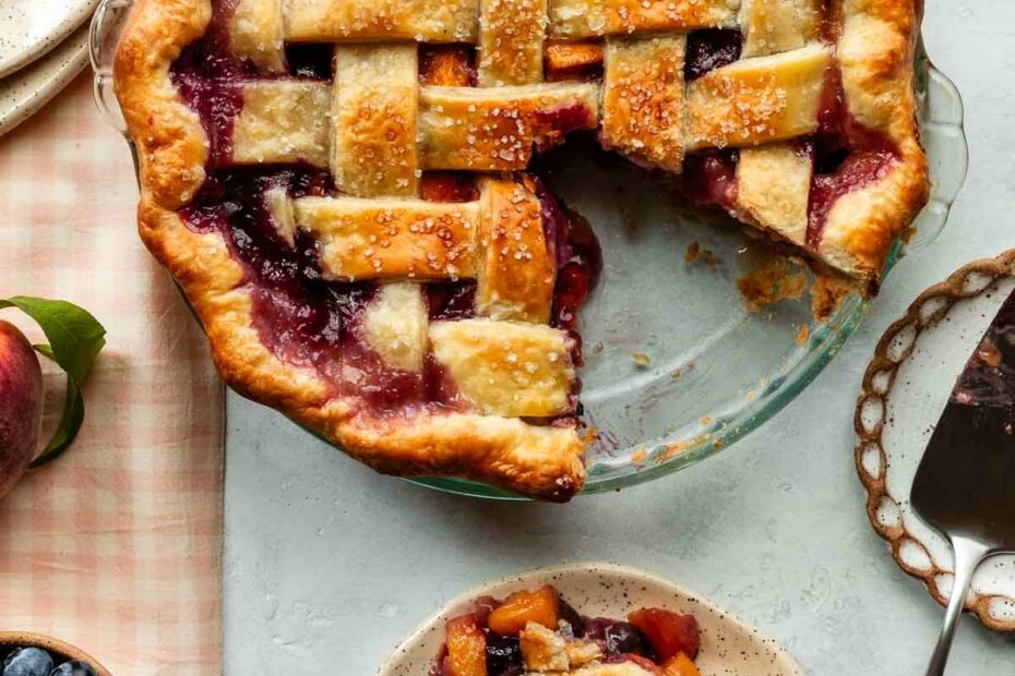 blueberry peach pie with lattice top with slice taken out.