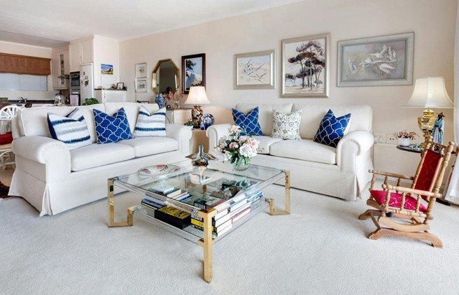 An elegant living room with framed artwork, white sofas, and bold cushions shows how to choose the right art pieces to complete your home design.