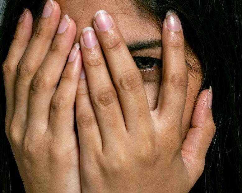 Woman with hands over her face hiding a blush