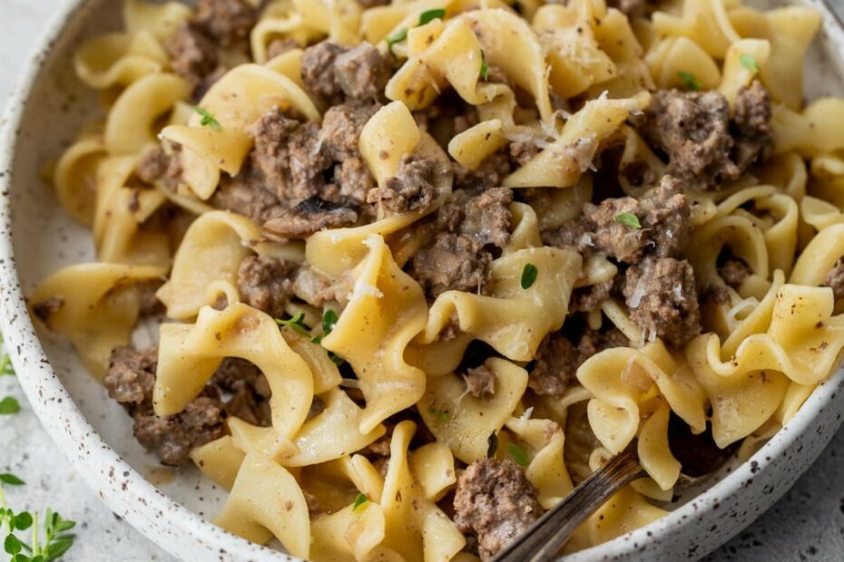 a fork in a bowl of beef and noodles.