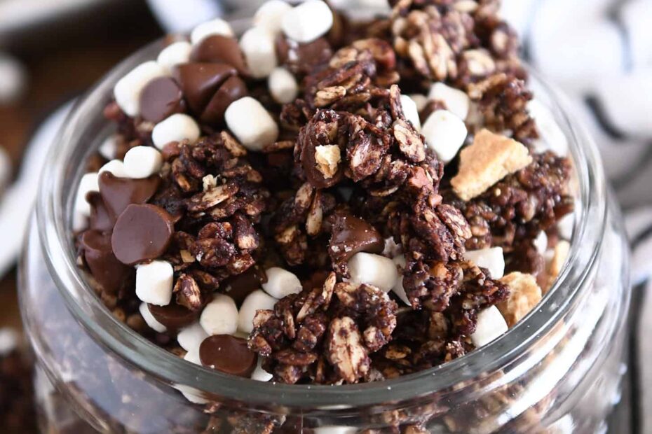 Glass jar filled with chocolate granola, graham cracker pieces and mini marshmallows.