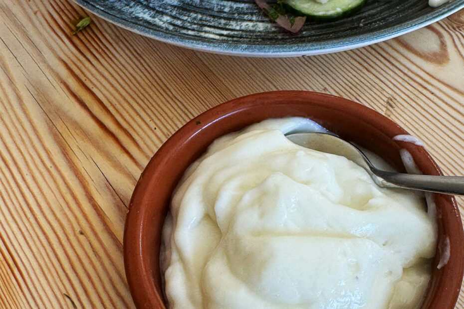 Garlic sauce with a kebab in the background.