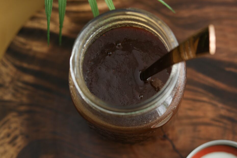Jar of glossy tamarind chutney with spoon inside.