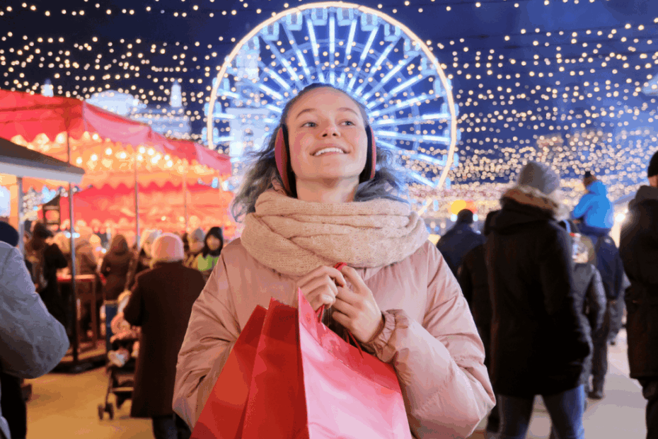 Happy teen girl with red shopping bags at Christmas market