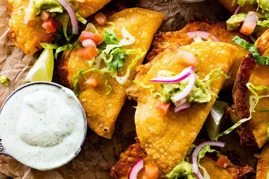 Crispy chicken tacos with fresh lettuce, tomatoes, cheese, red onions, and creamy sauce.
