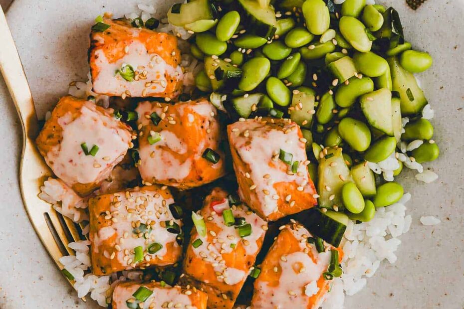 bang bang salmon bowl with cucumber edamame salad in a bowl with a golden fork