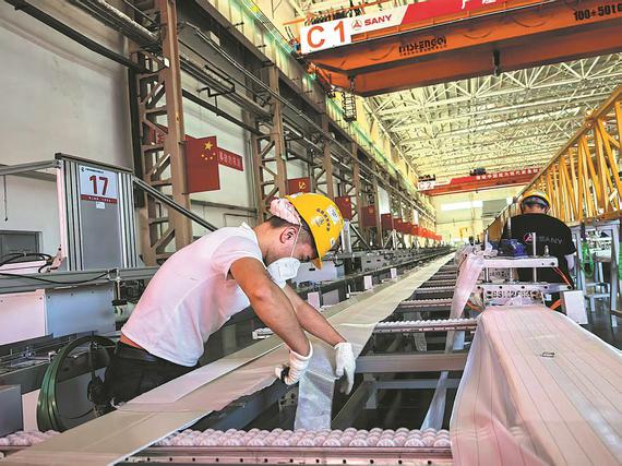 Workers assemble turbine blades at the wind power plant of Sany Heavy Industry in Tacheng, Xinjiang Uygur autonomous region, on Sept 12. (ZHAO YIMENG/CHINA DAILY)
