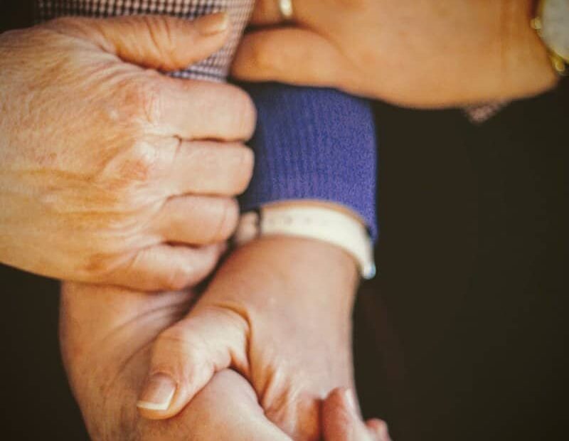 person in blue long sleeve shirt holding babys hand