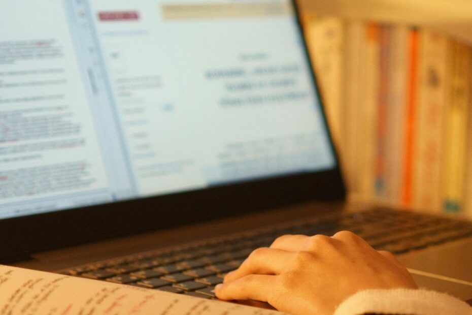 Someone working on a laptop with a notebook of handwritten notes beside them, capturing the idea of making steady progress over perfection.