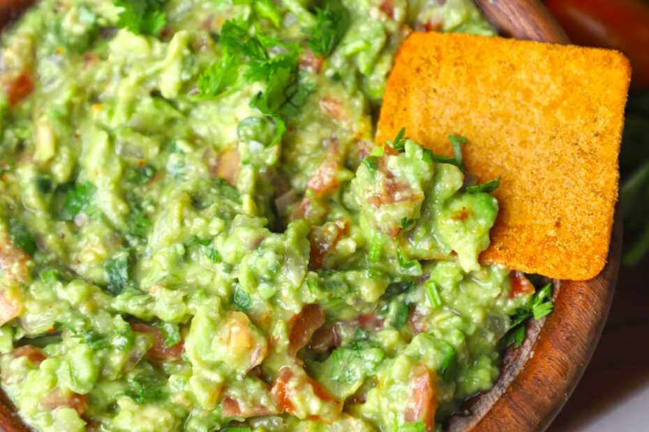 aerial close up shot of guacamole in a wooden bowl.