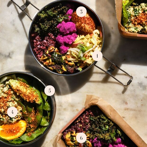 An Assortment of lunch ideas arranged on a table including hard-boiled egg, pickled cauliflower, edamame and a wedge of orange