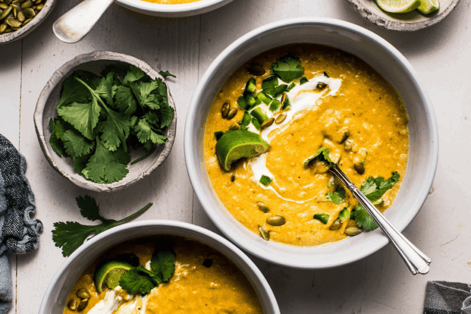 Overhead shot of creamy poblano soup that is swirled with sour cream and topped with pepitas.