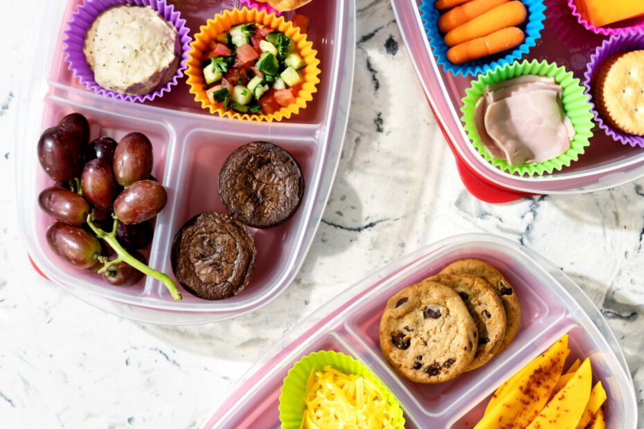 Homemade Lunchables in divided meal prep containers with cheese, crackers, fruit, and dips.