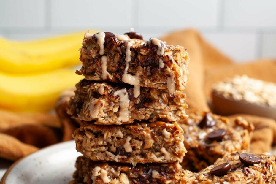 four peanut butter banana oat squares stacked on top of each other with two more on plate